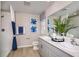 Well-lit bathroom featuring double sinks, blue and white accents, and a shower, creating a fresh and clean ambiance at 37252 Sagemoor Dr, Zephyrhills, FL 33541