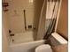 A full bathtub featuring a handheld shower head, safety bar, neutral tiles and curtain for privacy at 4814 Grist Mill Cir, New Port Richey, FL 34655
