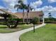 Beautiful community clubhouse with a walkway entrance, manicured landscaping and American flag at 4814 Grist Mill Cir, New Port Richey, FL 34655