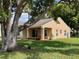 Exterior view of a peach-colored home with a manicured lawn and mature trees in a tranquil setting at 4814 Grist Mill Cir, New Port Richey, FL 34655