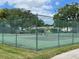 Well-maintained tennis court with a green fence and lush surroundings at 4814 Grist Mill Cir, New Port Richey, FL 34655