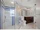 Bathroom showcasing a walk-in shower with glass shelving, commode and marble vanity at 5104 E Longboat Blvd, Tampa, FL 33615