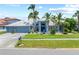 Charming single-story home featuring lush landscaping, a three-car garage, and a welcoming front lawn at 5104 E Longboat Blvd, Tampa, FL 33615