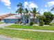 Charming home featuring a well-manicured lawn, lush landscaping, and inviting curb appeal with graceful palms at 5104 E Longboat Blvd, Tampa, FL 33615