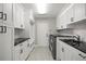 Bright laundry room with white cabinetry, black granite countertops, stainless steel washer and dryer, and tile flooring at 5104 E Longboat Blvd, Tampa, FL 33615