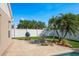 View of a well-maintained backyard with a grill, wooden chairs, table, and tropical landscaping at 632 Lake Cypress Cir, Oldsmar, FL 34677
