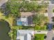 Aerial view of the property showing a well-maintained home with a pool, lush landscaping, and a serene pond at 7201 15Th Ne Ct, St Petersburg, FL 33702