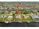Aerial view with arrow pointing to a canal-front property featuring a private dock, lush landscaping and quick access to the open water at 121 Colonial Sw St, Port Charlotte, FL 33952
