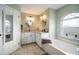 Bathroom showcasing double sinks, vanity, lighting, a window above the tub, and a framed mirror at 121 Colonial Sw St, Port Charlotte, FL 33952