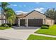 Inviting home exterior with a two-car garage, nice landscaping, and well-maintained lawn on a sunny day at 1430 Beaconsfield Dr, Wesley Chapel, FL 33543