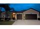 Charming home featuring a two-car garage, well-manicured lawn, and decorative palm tree at twilight at 1430 Beaconsfield Dr, Wesley Chapel, FL 33543