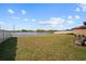 Spacious backyard with a view of the pond, enclosed by a white fence at 1547 Golden Glow Dr, Ruskin, FL 33570