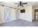 Bedroom featuring modern floors, barn door, television, and ceiling fan at 18236 Paradise Point Dr, Tampa, FL 33647