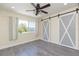 Bedroom featuring modern floors, barn door, curtains, large window, and ceiling fan at 18236 Paradise Point Dr, Tampa, FL 33647