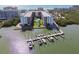 Aerial view of condominiums, a pool, a waterway, boat docks and surrounding foliage at 19531 Gulf Blvd # 210, Indian Shores, FL 33785