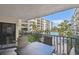 Condo balcony with a patio table overlooking pool, palm trees and neighboring buildings at 19531 Gulf Blvd # 210, Indian Shores, FL 33785