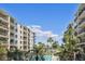 View of high-rise buildings and pool area featuring lots of palm trees and well-manicured landscaping at 19531 Gulf Blvd # 210, Indian Shores, FL 33785