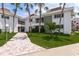 Charming condo building showcasing lush tropical landscaping and a welcoming brick walkway at 311 Island Way # 101, Clearwater Beach, FL 33767