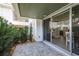 A covered patio leads inside through sliding glass doors, surrounded by lush greenery at 311 Island Way # 101, Clearwater Beach, FL 33767