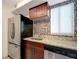 Modern kitchen featuring stainless steel refrigerator, granite countertops, and mosaic backsplash at 3206 W Azeele St # 126, Tampa, FL 33609