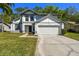Charming two-story home featuring a two-car garage, well-manicured lawn, and classic architectural details at 389 Waterford W Cir, Tarpon Springs, FL 34688