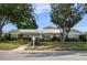 Inviting single-story home showcasing a well-kept lawn, mature trees, and a charming white and brick facade at 3918 Versailles Dr, Tampa, FL 33634