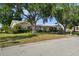 Inviting single-story home showcasing a well-kept lawn, mature trees, and a charming white and brick facade at 3918 Versailles Dr, Tampa, FL 33634