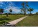 Picturesque golf course with paved path, lush green grass, and swaying palm trees on a sunny day at 3918 Versailles Dr, Tampa, FL 33634