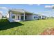 Backyard showcasing a covered patio, ample green space, and modern architectural details at 5979 Hidden Branch Dr, Apollo Beach, FL 33572
