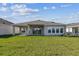 Expansive backyard with a covered patio and sliding glass doors providing seamless indoor-outdoor living at 5979 Hidden Branch Dr, Apollo Beach, FL 33572