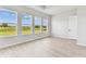 Light filled bedroom with wood-look floors and three large windows overlooking a lush green landscape at 5979 Hidden Branch Dr, Apollo Beach, FL 33572
