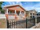 Charming single-Gathering home showcasing an orange exterior, black metal fence, and inviting front porch at 6414 N Central Ave, Tampa, FL 33604