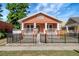 Charming bungalow with a black metal fence, orange stucco, and a covered front porch at 6414 N Central Ave, Tampa, FL 33604