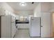 Kitchen featuring white cabinets and appliances, with tile flooring and an adjacent doorway at 6414 N Central Ave, Tampa, FL 33604