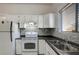 Bright kitchen featuring white cabinets, stainless steel sink, oven, and grey backsplash at 6414 N Central Ave, Tampa, FL 33604