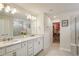 Bright primary bathroom features double sink vanity with quartz countertop, walk-in closet and glass enclosed shower at 10815 Windswept Garden Way, Tampa, FL 33647