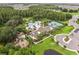 Aerial view of a community featuring a pool, clubhouse, tennis courts, and playground surrounded by mature trees at 10815 Windswept Garden Way, Tampa, FL 33647