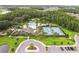 Aerial image of a community pool and tennis courts surrounded by palm trees and lush greenery at 10815 Windswept Garden Way, Tampa, FL 33647