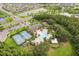 A high angle shot of community amenities including a pool, tennis courts, playground, and clubhouse nestled amidst lakes and trees at 10815 Windswept Garden Way, Tampa, FL 33647
