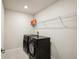 Well-lit laundry room with a modern black washer and dryer, and wire shelving for storage at 10815 Windswept Garden Way, Tampa, FL 33647