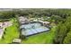 Aerial shot of tennis courts surrounded by lush greenery and tropical palms in a vibrant community setting at 10815 Windswept Garden Way, Tampa, FL 33647