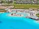 Aerial view showcases the lagoon island with palm trees, beach chairs, and clear waters at 10937 Penny Gale Loop, San Antonio, FL 33576