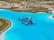 Aerial view of the community lagoon with an inflatable water park and sandy beach at 10937 Penny Gale Loop, San Antonio, FL 33576