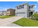 Charming two-story home featuring a two-car garage, green lawn, and covered entryway with a hanging chair at 10937 Penny Gale Loop, San Antonio, FL 33576