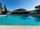 Large community pool with lounge chairs and a recreation building in the background at 1423 Pine Glen Ln # D2, Tarpon Springs, FL 34688