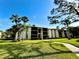 Exterior building view with walkway, lawn, trees, and partial blue sky at 1423 Pine Glen Ln # D2, Tarpon Springs, FL 34688