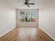 A neutral bedroom with wood floors, a large window, and a ceiling fan at 2009 River Turia Cir, Riverview, FL 33578