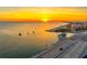 Aerial view of a serene sunset over the ocean, with a bridge and building silhouetted in the foreground at 248 137Th Cir, Madeira Beach, FL 33708