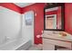 Bathroom featuring red walls, white bathtub, window, mirror, sink, and white cabinets at 248 137Th Cir, Madeira Beach, FL 33708