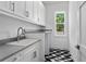 Modern laundry room with geometric patterned floor, sink and light gray countertop space at 3406 W Alline Ave, Tampa, FL 33611